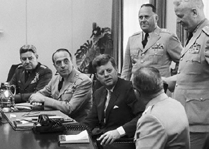 President John F Kennedy amidst his military advisors during the Cuban Missile Crisis in October 1962. Copyright The Daily Banter.